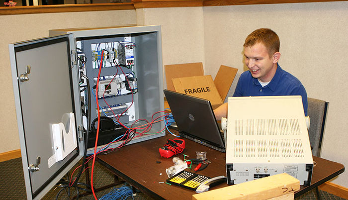 A man uses his laptop to to program a PLC unit