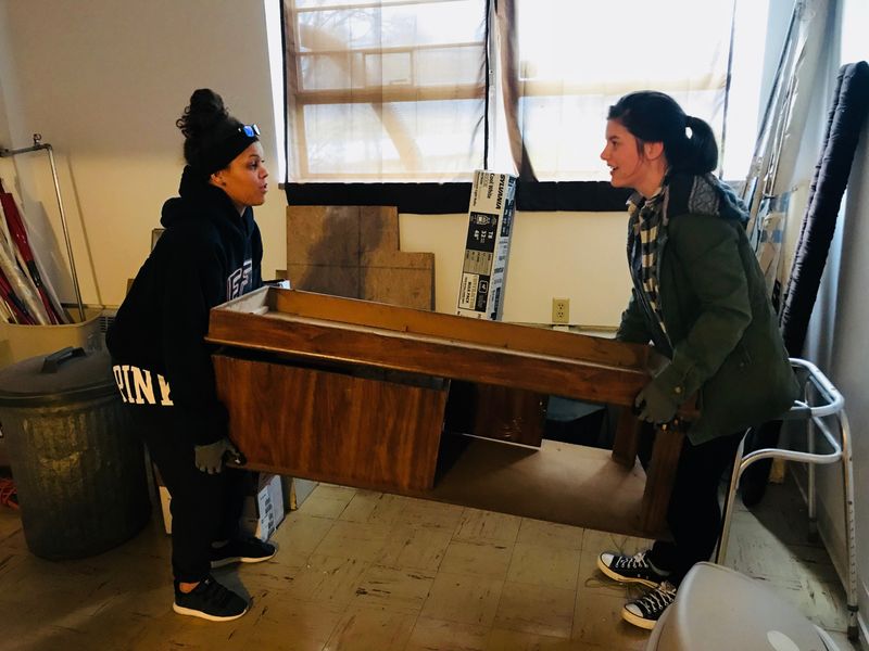 Two students carry table during community service project at local animal shelter