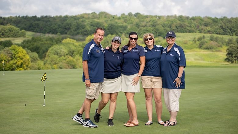 Men and women pose for photo on golf course green