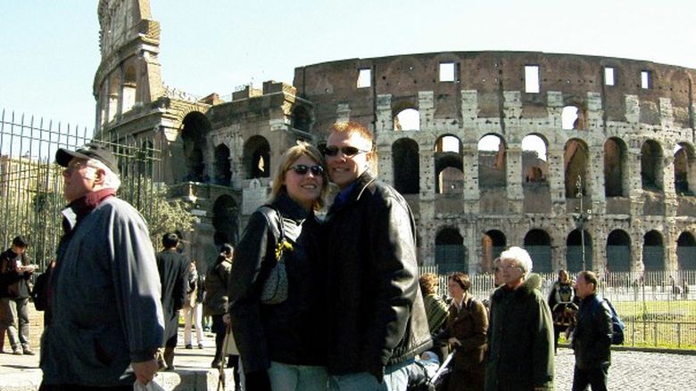 Man and woman stand in front of Coloseum in Italy