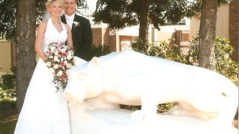 Bride and groom stand next to lion statue 