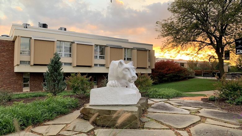 Nittany lion statue in foreground with campus buildings in background