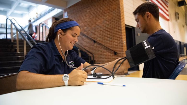 Athletic trainer takes blood pressure of student-athlete