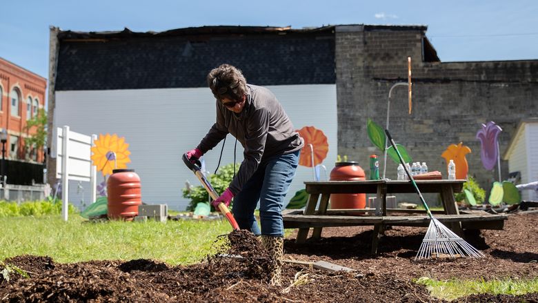 Woman shovels mulch at community garden