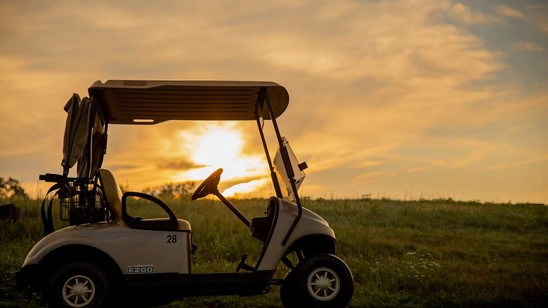 Sunrise behind golf cart on golf course
