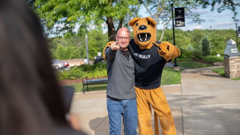 Man stands next to Nittany Lion mascot