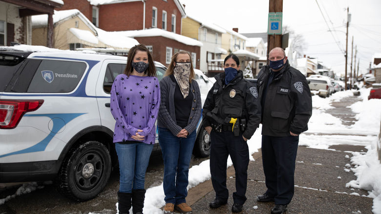 Four individuals stand outside wearing masks