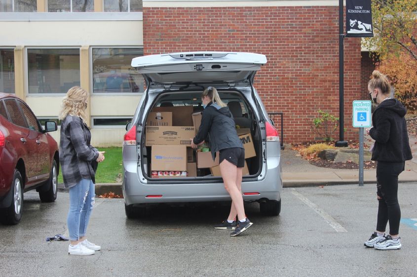 Student loads food donations into car