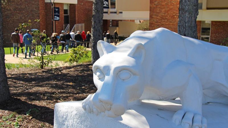 Tour group passes behind lion shrine at Penn State New Kensington