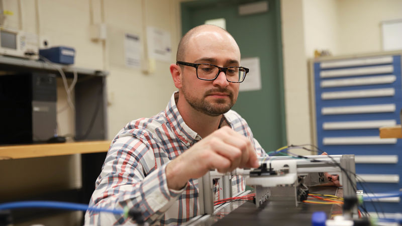 Joseph Cuiffi wiring conveyor belt in lab