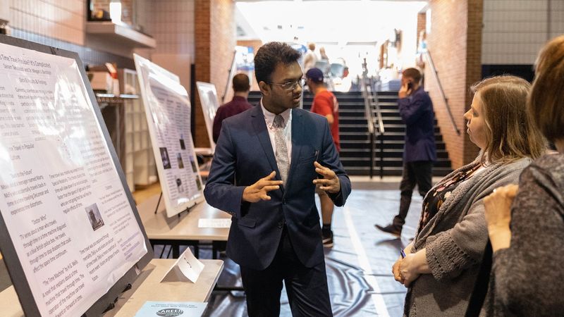 Male student presents research project to two females