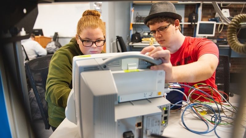 Two students work on hospital equipment in lab Two students work on hospital equipment in lab