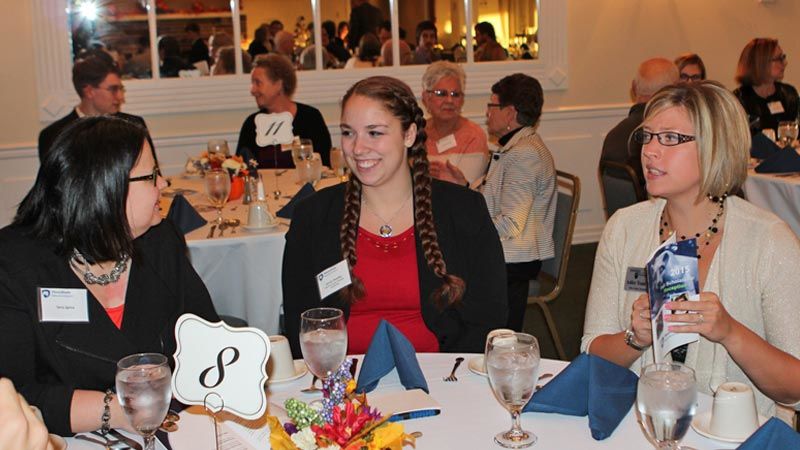 Headley and two members of the Alumni Society seated at a round table at the Scholarship Reception