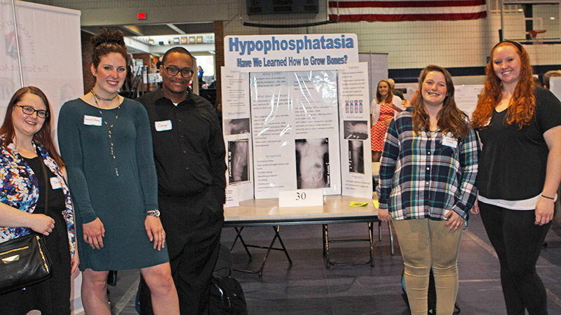 5 radiological sciences students stand in front of their poster at the annual Research & Creative Expo