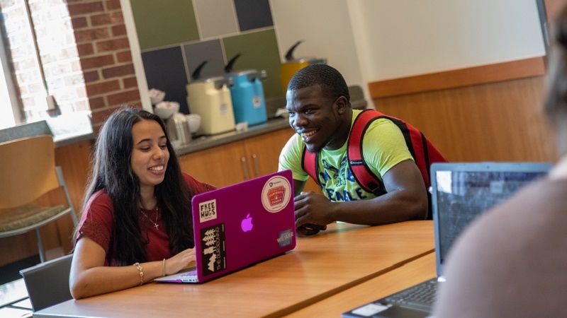 Students sit at table with laptop Students sit at table with laptop