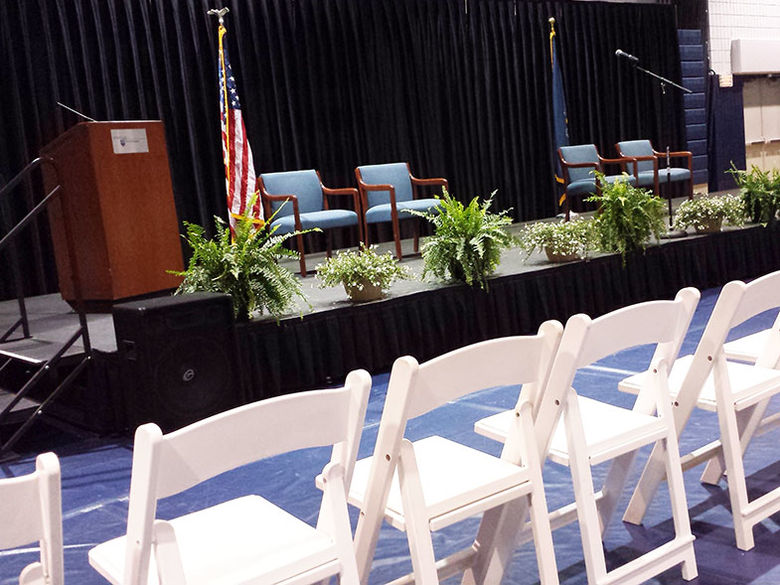 Chairs, podium, and stage set up in the gym for commencement