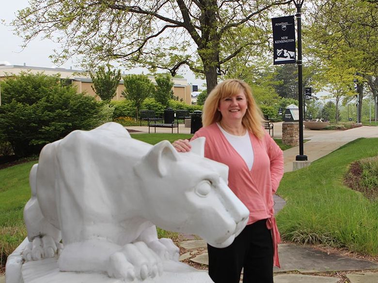 Mary, the campus registrar, stands beside the lion shrine 