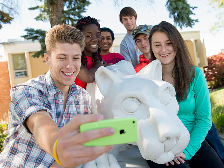 A group of students take a selfie at the campus lion shrine