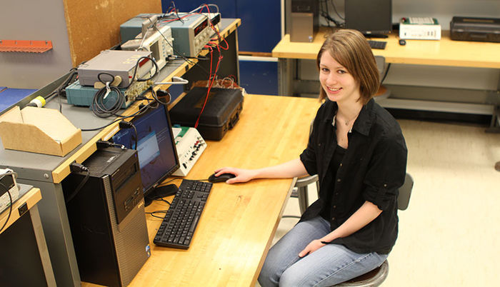 A former student in front of a computer in an EMET lab