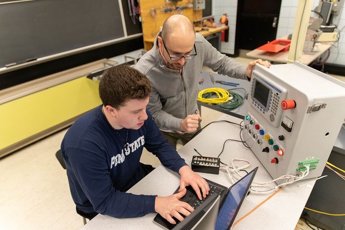 Student and professor stand by computer
