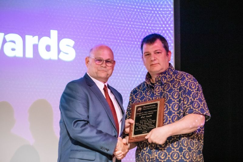 Two individuals standing and holding plaque