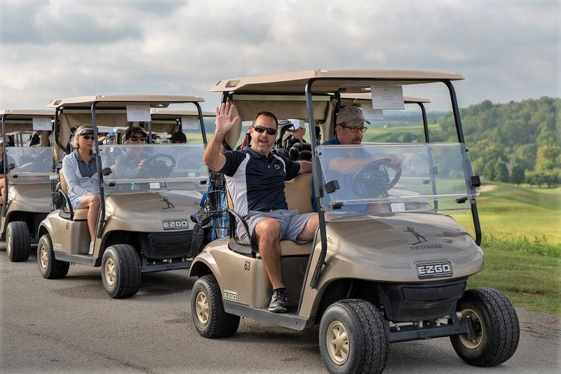 Man waves from golf cart