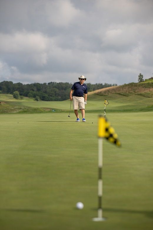 Man watches golf ball on green after putt