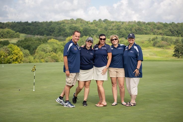 Men and women pose for photo on golf course green