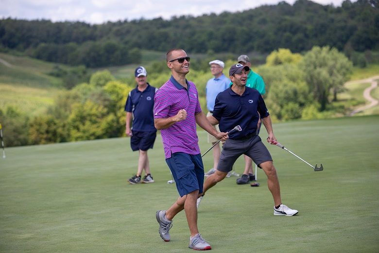 Man smiles holding golf putter