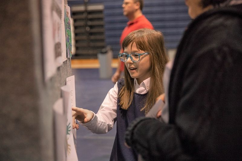 Girl points at paper hung on wall