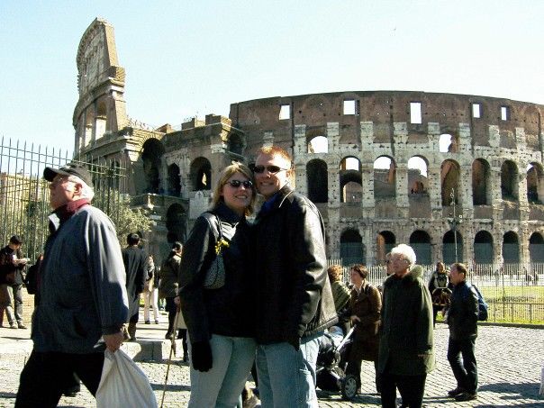 Man and woman stand in front of Coloseum in Italy