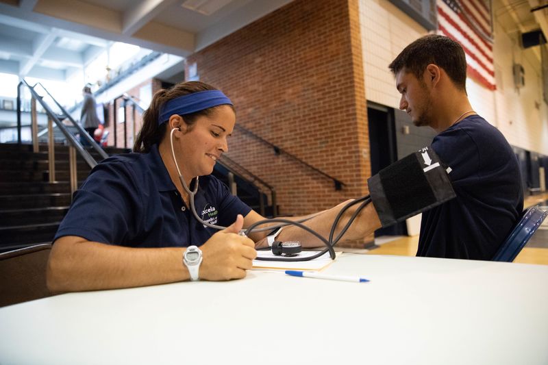Athletic trainer takes blood pressure of student-athlete Athletic trainer takes blood pressure of student-athlete