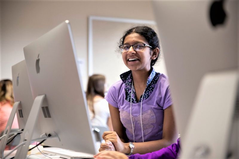 Female student sits by computers