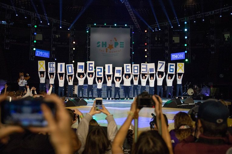 Students hold signs showing $10,621,683.76