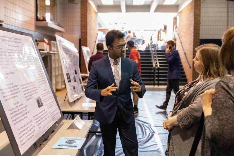 Male student presents research project to two females