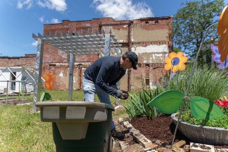 Man puts mulch in garden bed Man puts mulch in garden bed