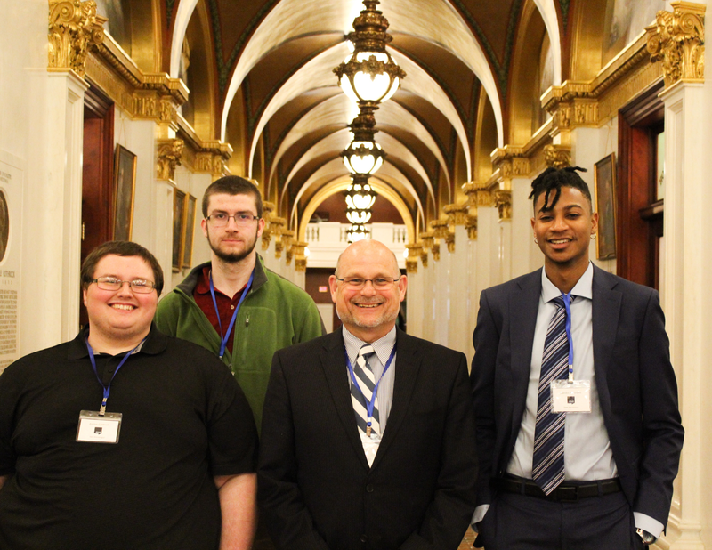 3 students and chancellor stand for photo