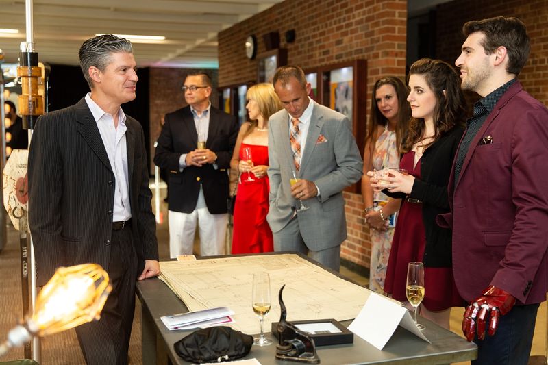 Man speaks with group around desk