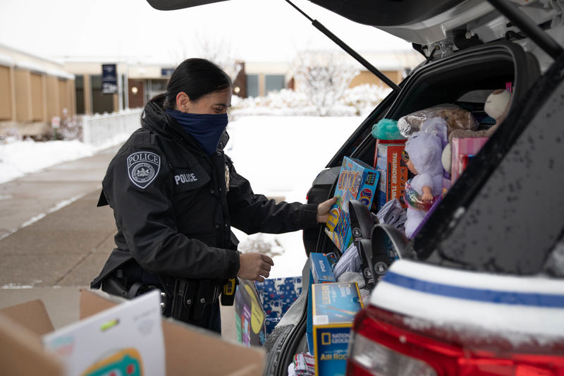 Police officer loading police cruiser with donated items