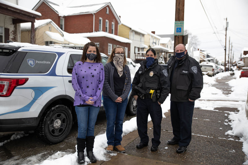 Four individuals stand outside wearing masks