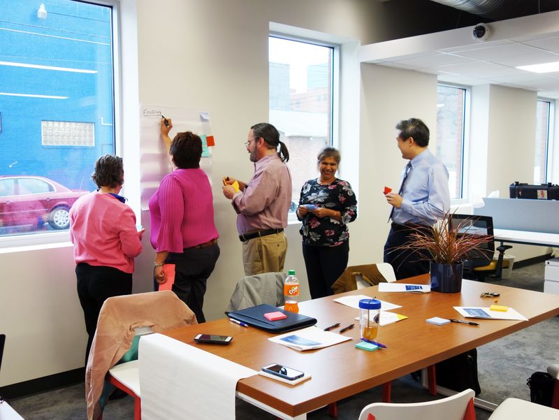 Faculty and staff posting notes on a large sheet of paper hanging on wall Faculty and staff posting notes on a large sheet of paper hanging on wall