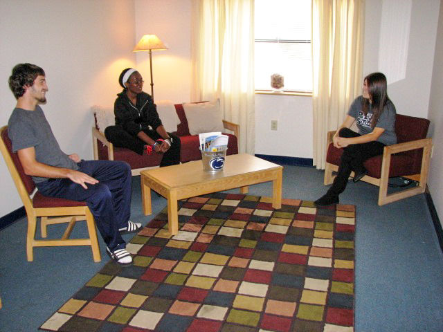 A living room with students seated around a table
