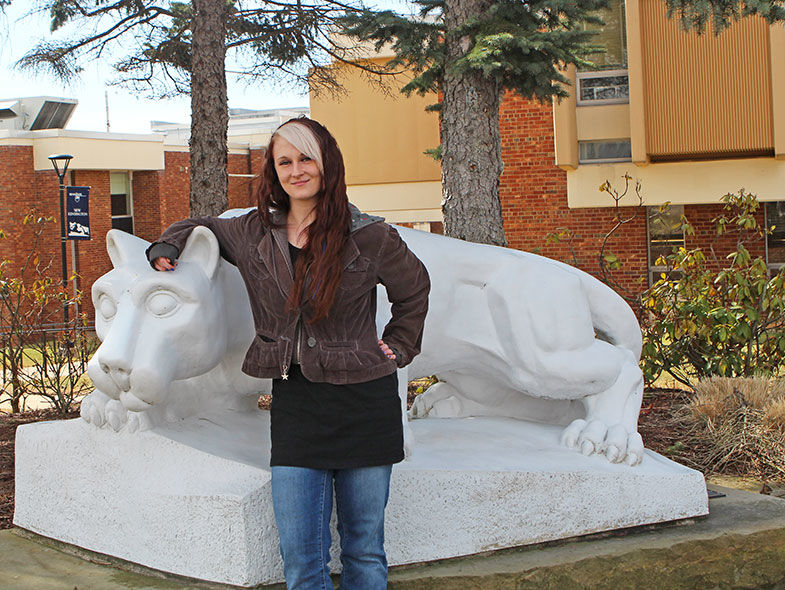 An Administration of Justice alumna stands next to the campus lion shrine