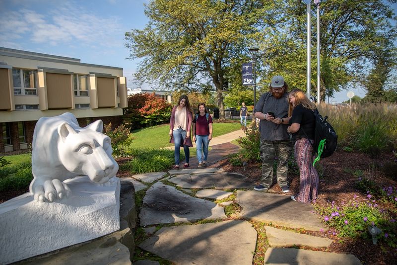 Students standing and walking by lion statue