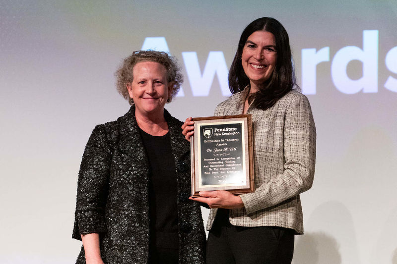 Faculty member accepts award plaque from director of academic affairs