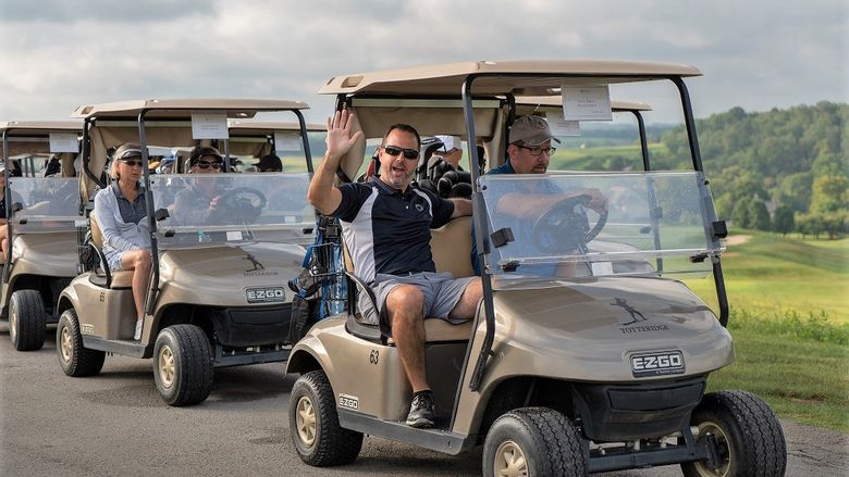 Man waves from golf cart