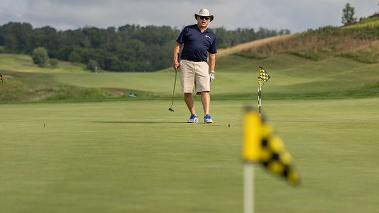 Man watches golf ball on green after putt