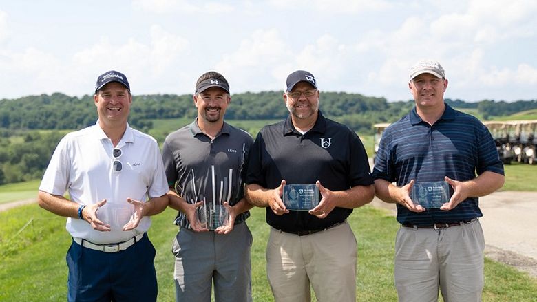 Four golfers holding trophies