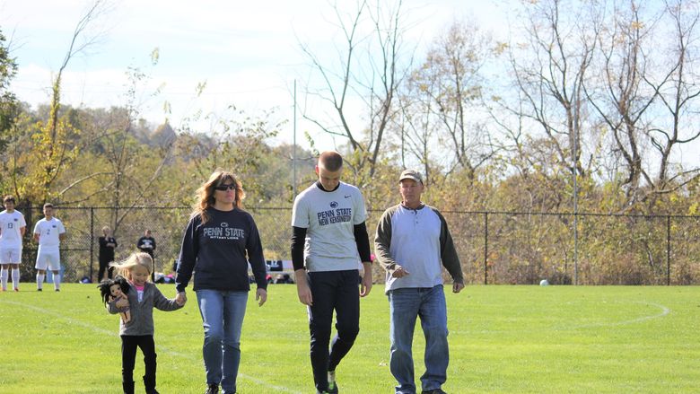 Four people walk across soccer field