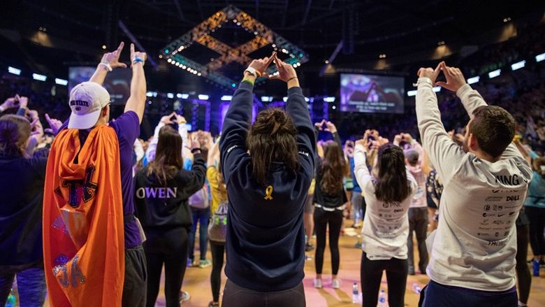 Three students hold up hands in diamond formation for THON